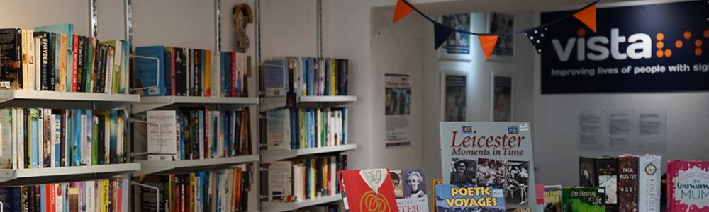 A selection of books on display in one of Vista's shops, with the Vista logo mounted on the wall behind.